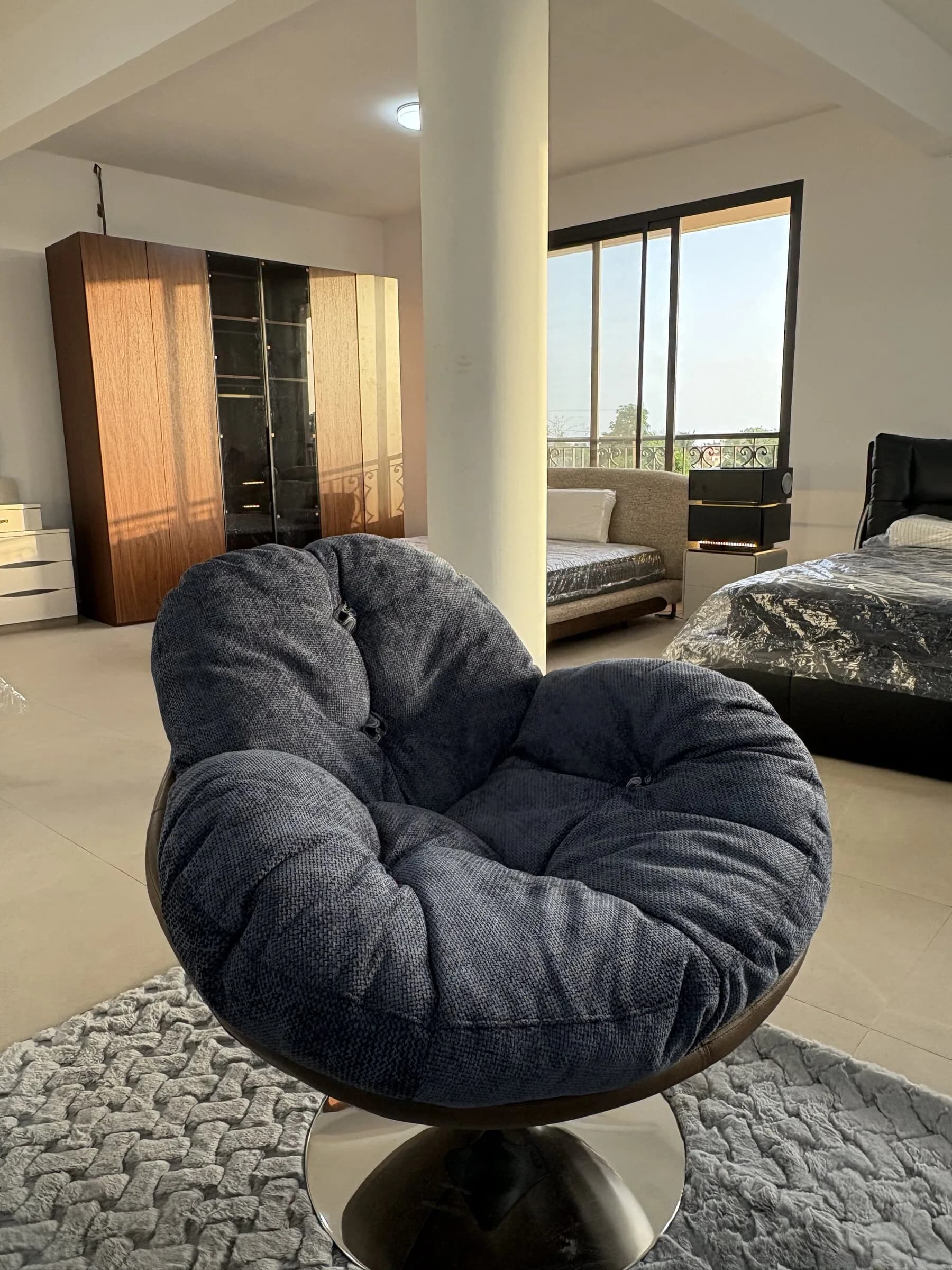 Fauteuil cocon pivotant en tissu bleu nuit sur pied chromé