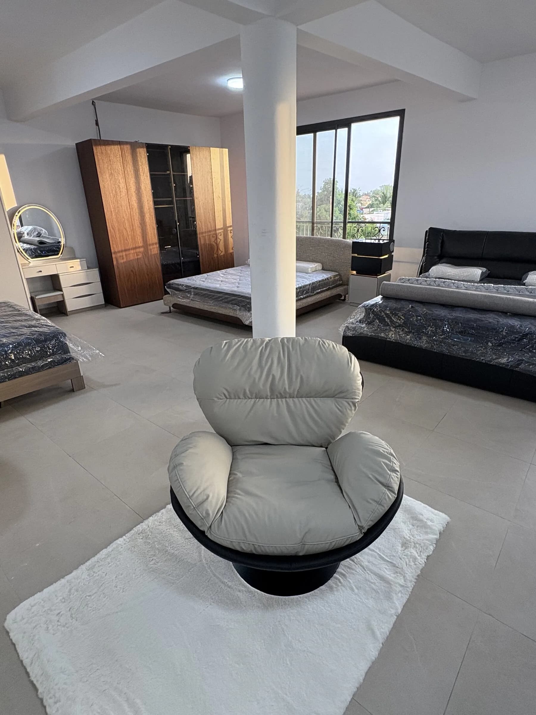 Fauteuil cocon pivotant gris perle sur piètement noir, exposé dans le showroom — vue 3