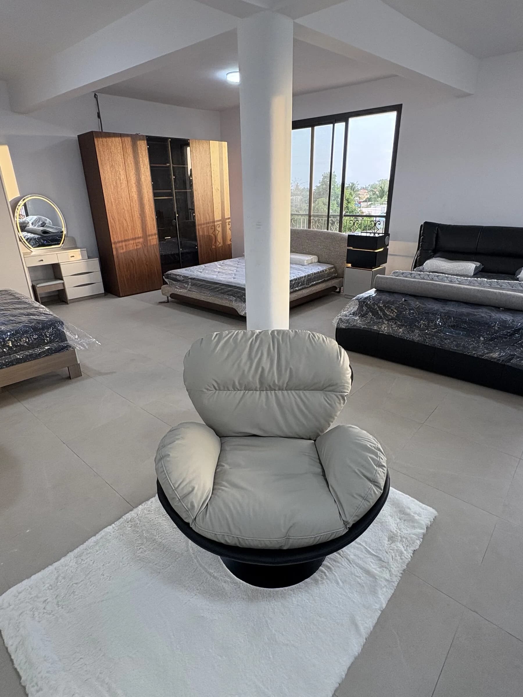 Fauteuil cocon pivotant gris perle sur piètement noir, exposé dans le showroom — vue 4